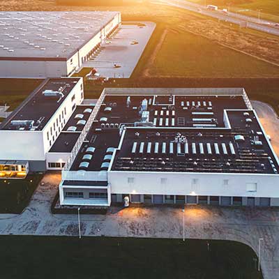 Ariel view of a large commercial warehouse with a black, flat roof during sunset