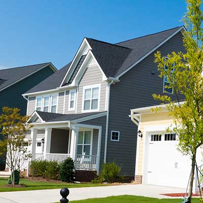 Front view of a mid-class, two-story home along a row of other homes in a suburb area
